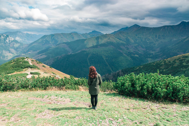 Brunette girl on the background of landscape and green mountains - 写真・画像