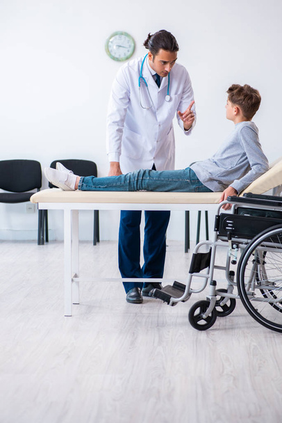 Young male doctor pediatrist and boy in wheel-chair - Foto, Imagen