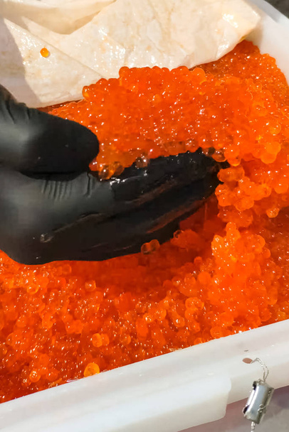 Mixing eggs with gloved hand. red caviar in a plastic container. - Photo, Image