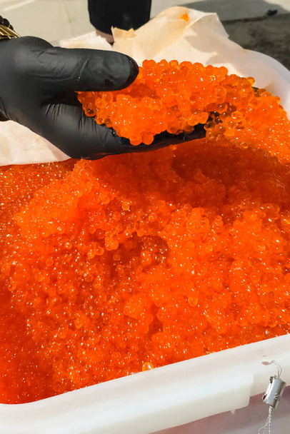 Mixing eggs with gloved hand. red caviar in a plastic container. - Photo, Image