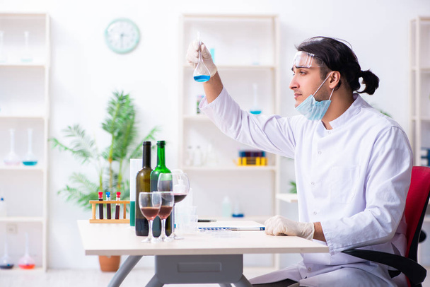 Químico masculino examinando muestras de vino en el laboratorio - Foto, imagen