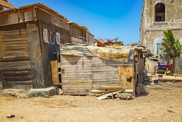 A typical wooden crumbled shack stands on dusty land in the middle of Goree, Seengal. It's near Dakar, Africa. There's a mess and washing on the roof. - Photo, Image
