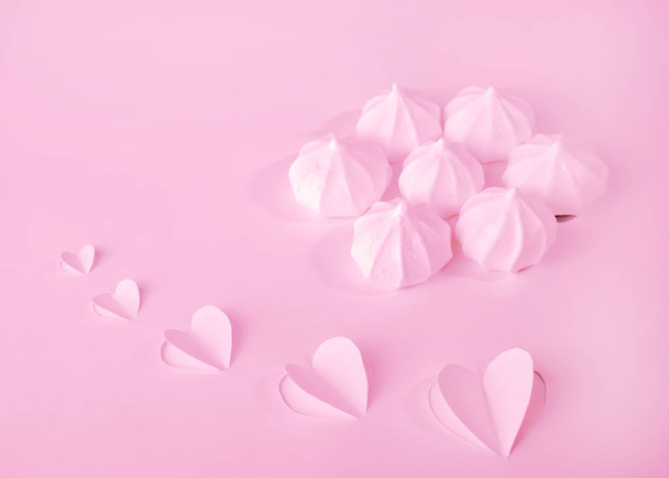 A gentle meringue kiss. Pink monochrome. On the background with hearts on Valentine's Day. Selective focus. - Fotó, kép