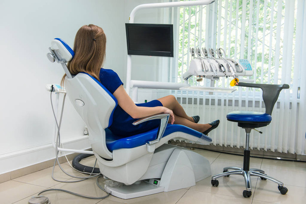 Fiatal lány beteg vár egy orvos a fogorvosi székben a klinikán - Fotó, kép