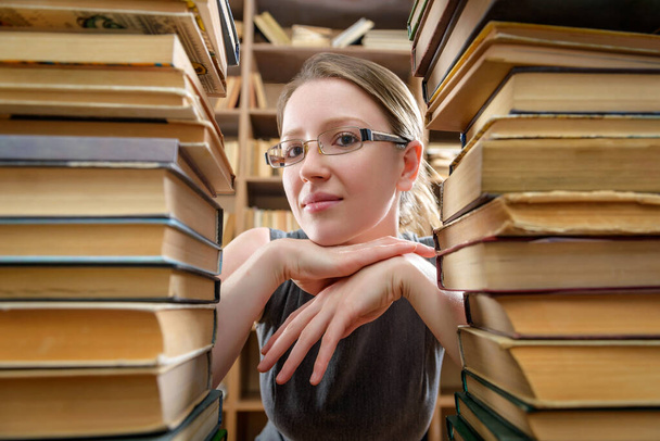 Fille en lunettes avec de vieux livres dans la bibliothèque
 - Photo, image