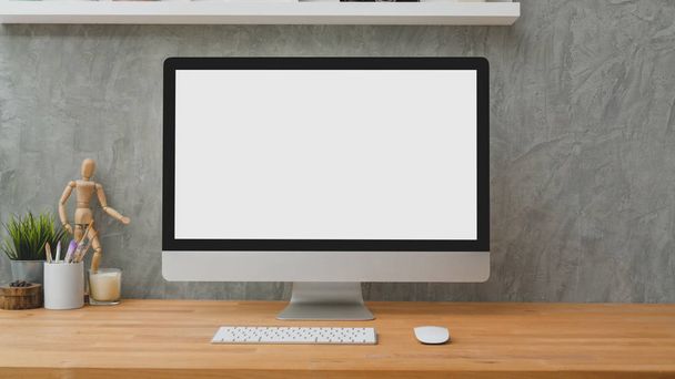 Cropped shot of blank screen desktop computer with decorations on wooden table with loft gray wall background - Photo, Image