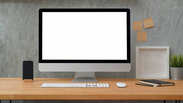 Закройте вид на настольный компьютер с плоским экраном, на котором виднеются записки, рамки и канцелярские принадлежности на фоне серых стен чердака
 - Фото, изображение