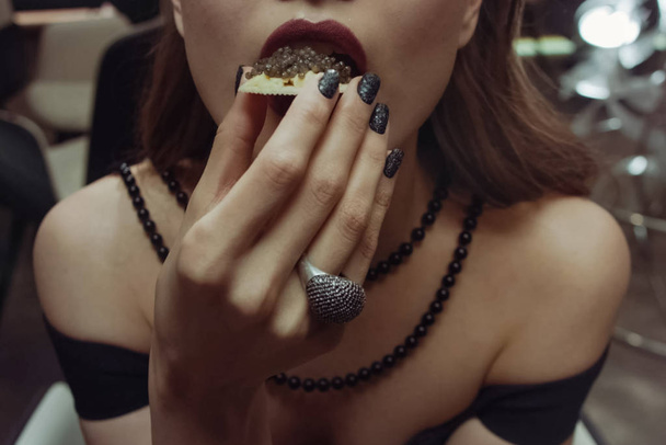 Mulher comendo sanduíche com caviar preto
. - Foto, Imagem
