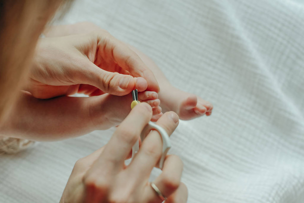 Родители держат в руках ножницы для обрезки детского ногтя
 - Фото, изображение