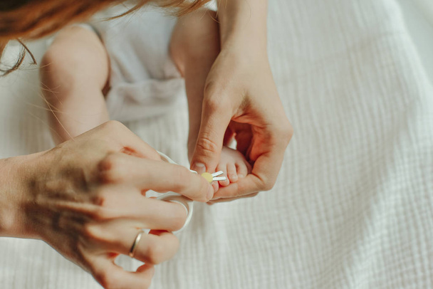 Parent hand holding scissors trimming child toenail - Foto, Imagen