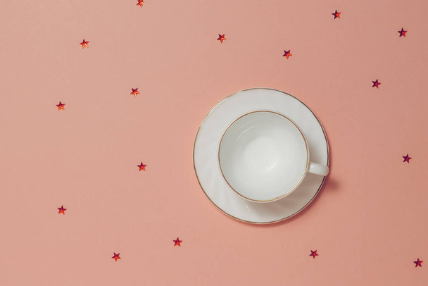 Copo de café branco com pires em fundo rosa com estrelas
. - Foto, Imagem