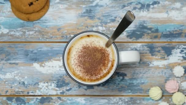 Kézzel hozzá kakaó és keverő kávé cappuccino egy csésze fa asztalon, felső nézet - Felvétel, videó