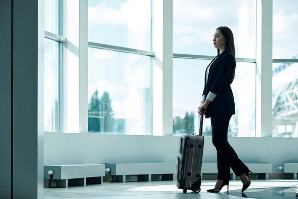 Young asian business woman in airport with baggage trolley bag, waiting for departure - Zdjęcie, obraz