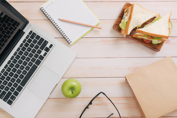 Caja de almuerzo con sándwiches y fruta en el fondo del lugar de trabajo
 - Foto, imagen