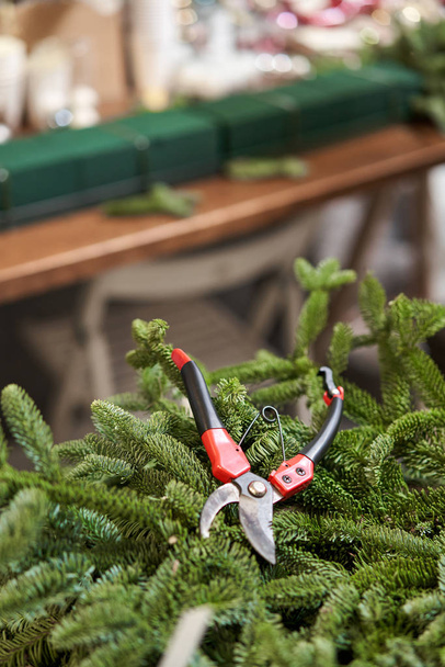 Closeup secateur on spruce branches. Christmas arrangement. Master class on making decorative ornaments. Christmas decor with their own hands. The new year celebration. Flower shop - Photo, Image
