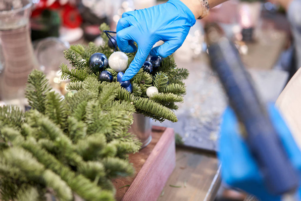 A woman decorates a Christmas arrangement. Master class on making decorative ornaments. Christmas decor with their own hands. The new year celebration. Flower shop - Photo, Image
