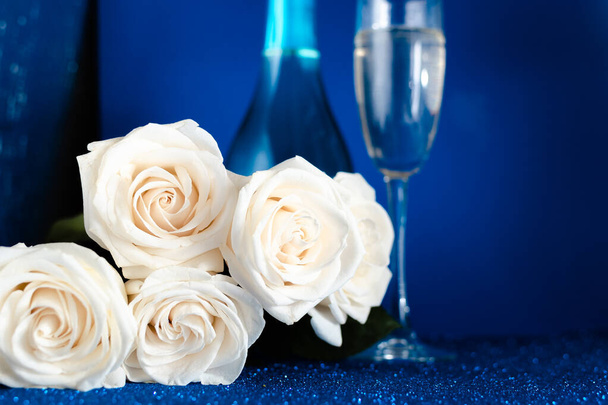 Dos copas de champán frío y un ramo de rosas blancas sobre fondo azul clásico. San Valentín
 - Foto, Imagen
