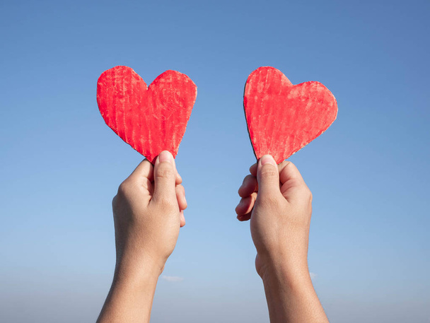 Kezek kezében két piros szív alakú újrahasznosított karton kék szk - Fotó, kép