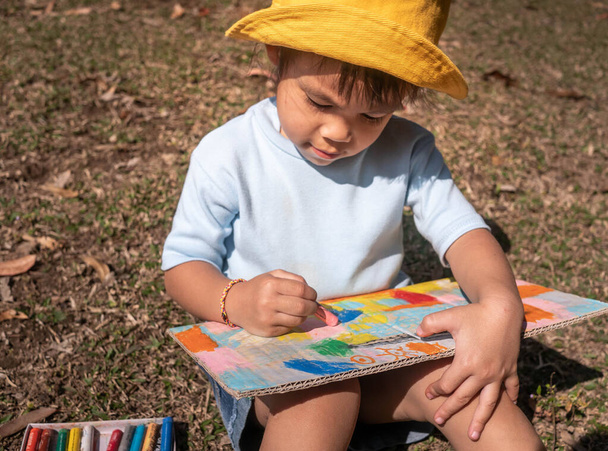 La pequeña niña artista sentada y pintando en el reciclaje
 - Foto, Imagen