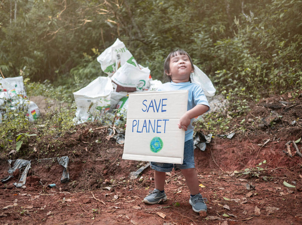 Το μικρό κορίτσι κρατώντας "Σώστε τον πλανήτη" Αφίσα δείχνει ένα - Φωτογραφία, εικόνα