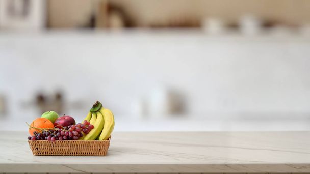 Bulanık mutfak odasıyla mermer masanın üzerindeki meyve sepetinin görüntüsünü kapat. - Fotoğraf, Görsel