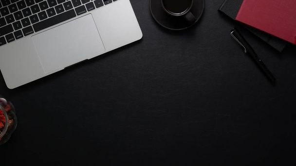 Vista dall'alto del luogo di lavoro scuro con computer portatile, forniture per ufficio e spazio per copiare sul tavolo nero
 - Foto, immagini