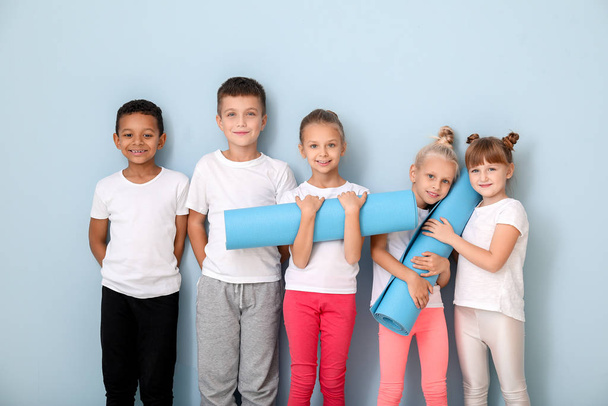 Маленькі діти з йога килимками біля кольорової стіни
 - Фото, зображення