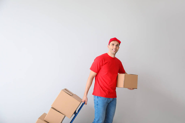 Uomo di consegna con scatole su sfondo chiaro
 - Foto, immagini