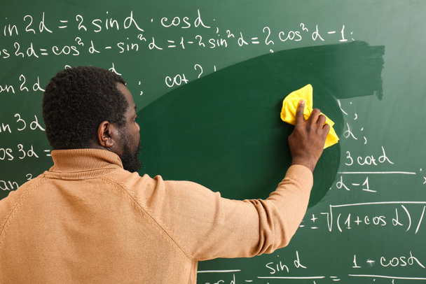 Учитель афроамериканской математики вытирает доску в классе
 - Фото, изображение