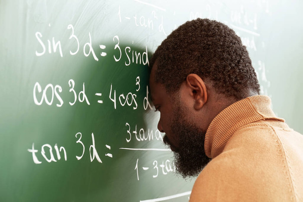 Афро-американский учитель математики в отчаянии рядом с доской
 - Фото, изображение