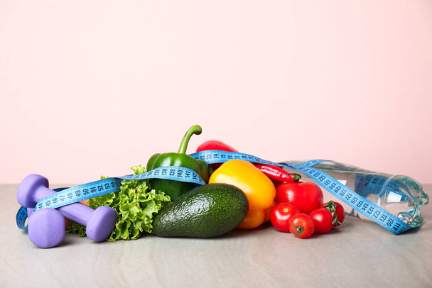 Different healthy food with measuring tape and dumbbells on table. Diet concept - Photo, Image
