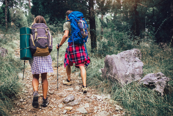Усміхнена пара ходить з рюкзаками на природному тлі
 - Фото, зображення