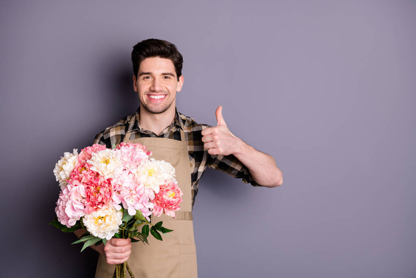 Photo of cheerful handsome man wearing checkered shirt showing thumb up leaving feedback about flower shop isolated grey color background - 写真・画像