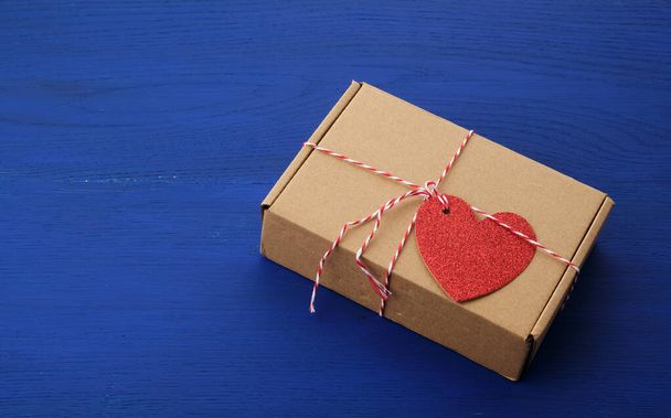 caja marrón rectangular con un regalo y un corazón de papel rojo atado a
  - Foto, imagen