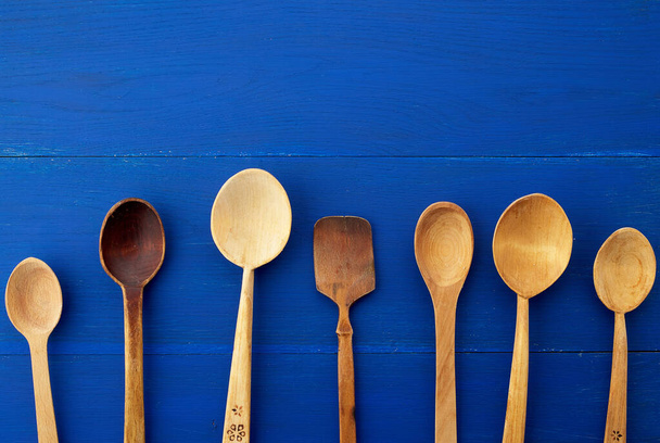 set of yellow wooden vintage spoons on a blue wooden background - Foto, immagini