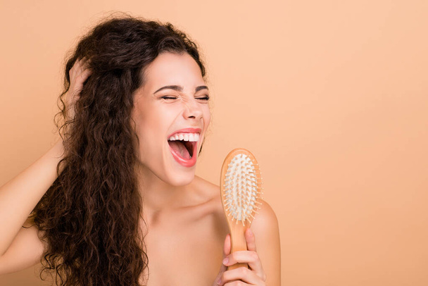 Close-up portrait of her she nice attractive gorgeous winsome cheerful glad wavy-haired girl using new professional comb like mic shower isolated over beige pastel background - Foto, Imagem
