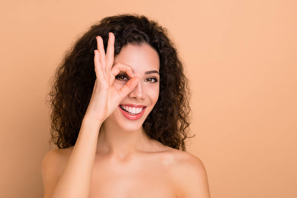 Close-up portrait of her she nice-looking attractive sweet gorgeous cheerful cheery wavy-haired girl showing ok-sign on one eye party preparation disco leisure isolated over beige background - Fotoğraf, Görsel