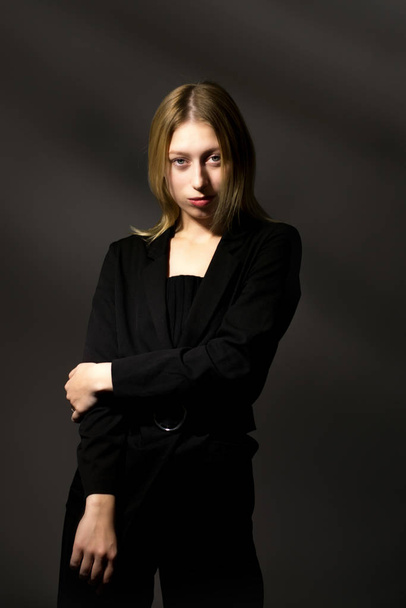 blonde in a black suit on a black background. Business woman - Фото, изображение