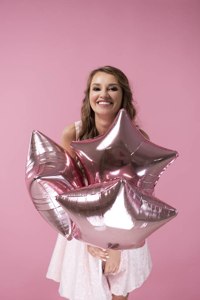 Happy woman with star shaped balloons on the pink background  - Φωτογραφία, εικόνα