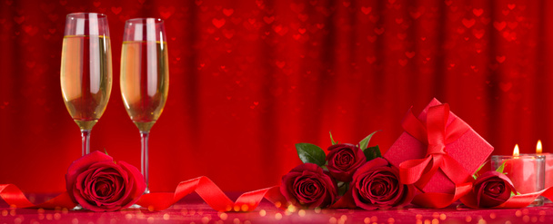Celebration dinner concept. Champagne glasses, gift package and roses on table - Фото, изображение