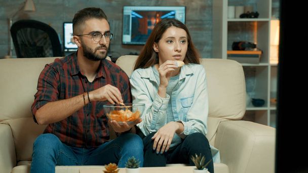 Концентрована кавказька молода пара під час перегляду телевізора
 - Фото, зображення