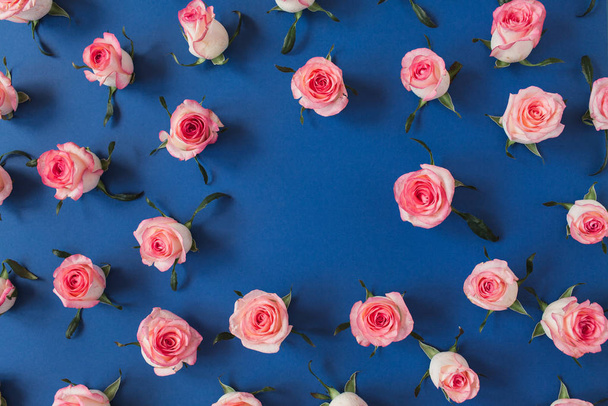 Ronde frame rand van roze roos bloemknoppen op blauwe achtergrond. Mockup blanco kopieerruimte. Platte lay, bovenaanzicht bloemsamenstelling. - Foto, afbeelding