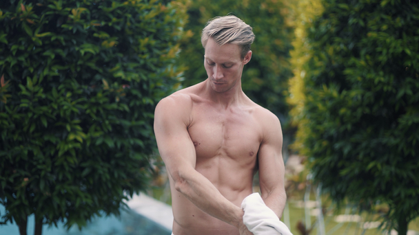 Sexy muž bez trička si utírá obličej a tělo ručníkem po koupání v bazénu - Záběry, video