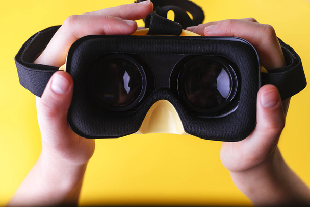 Manos de mujer blanca sosteniendo gafas de realidad virtual amarillas
 - Foto, imagen