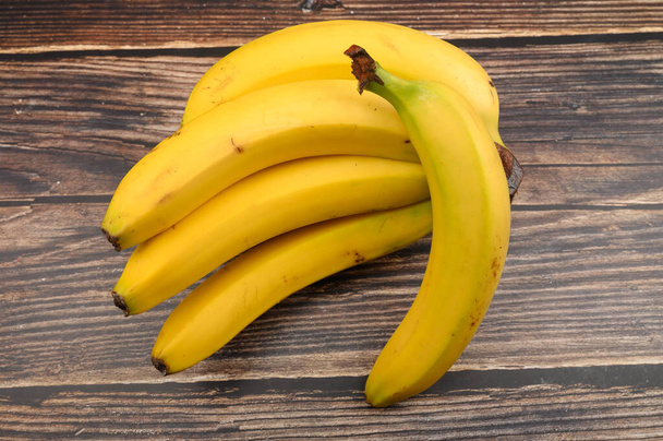 Куча спелых желтых бананов на деревянном фоне. Закрыть
. - Фото, изображение