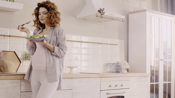 zwangere vrouw eet heerlijke salade in de keuken - Video