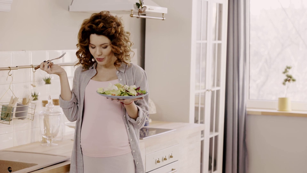 raskaana oleva nainen syö maukasta salaattia keittiössä
 - Materiaali, video