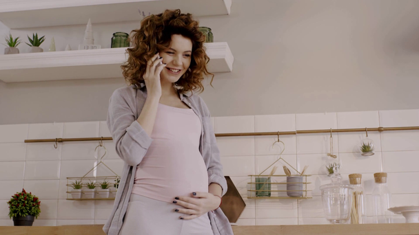 šťastná těhotná žena mluví na smartphone a dotýká břicho - Záběry, video