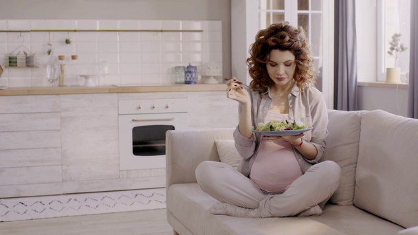 donna incinta mangiare insalata mentre seduto sul divano in cucina
 - Filmati, video