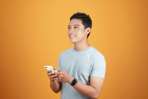 Smart casual asian man using smartphone in orange background. - Photo, Image